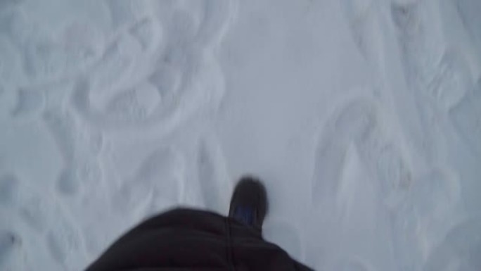 冬天，一个穿着黑色靴子和牛仔裤的男人的腿在雪地里行走。视点视频