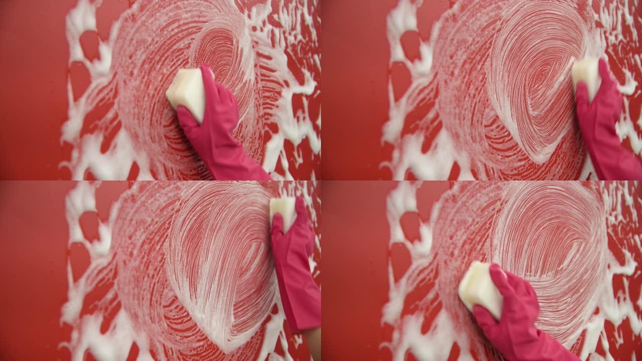 女人用海绵手清洁红墙