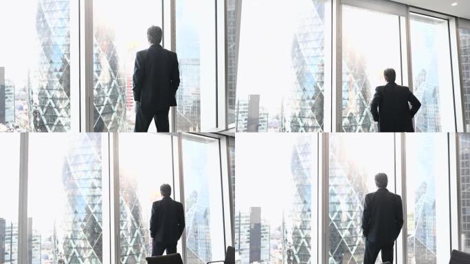 一名男性高管从办公室窗口望向伦敦金融城