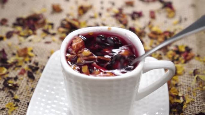 用勺子蘸满一杯注入的花草果茶，放在质朴的黄麻粗麻布上