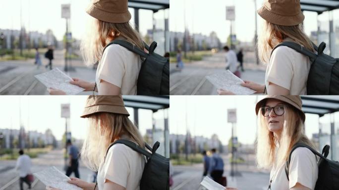 年轻的旅游女子背着背包在地图上寻找正确的方向，在户外的电车站等待公共交通工具。去欧洲旅行
