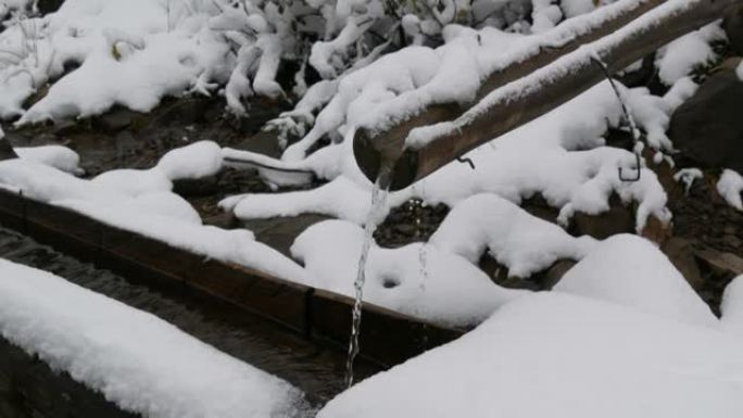 大雪清洁，透明的山水流从木制排水沟流入特殊槽