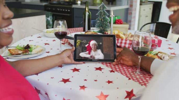 微笑的非洲裔美国夫妇使用平板电脑与屏幕上的幸福女人进行圣诞节视频通话