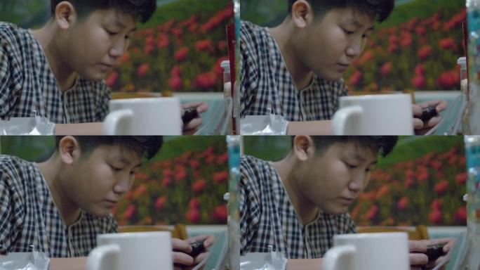 亚洲男孩晚上在家坐在椅子上玩手机游戏，生活方式概念。