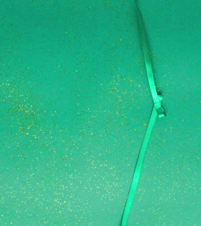 翡翠绿色缎带蝴蝶结，用金色闪光绑在绿色上并解开。停止运动垂直动画圣诞假期，并呈现概念平铺与复制空间。