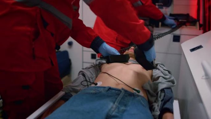 急救医生在救护车中对患者使用心脏除颤器