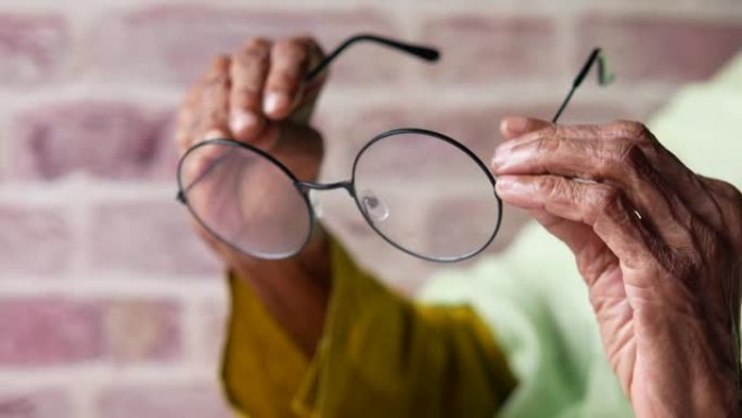 老年女性手持旧眼镜的特写
