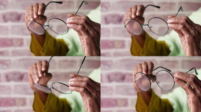 老年女性手持旧眼镜的特写