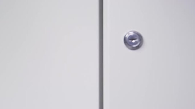 狡猾的学生试图用长铝尺极端特写从里面用锁打开学校储物柜的灰色金属门