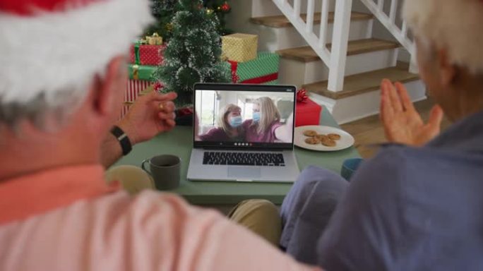 快乐的非洲裔美国高级夫妇在圣诞节与戴着口罩的女性朋友进行视频通话