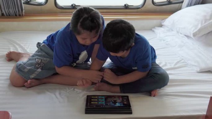 亚洲兄弟姐妹在大篷车上使用平板电脑。当他们在夏日躺在前面时。房车假日旅行