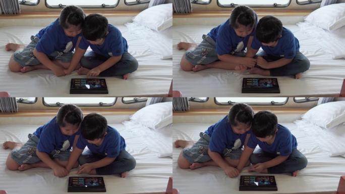 亚洲兄弟姐妹在大篷车上使用平板电脑。当他们在夏日躺在前面时。房车假日旅行