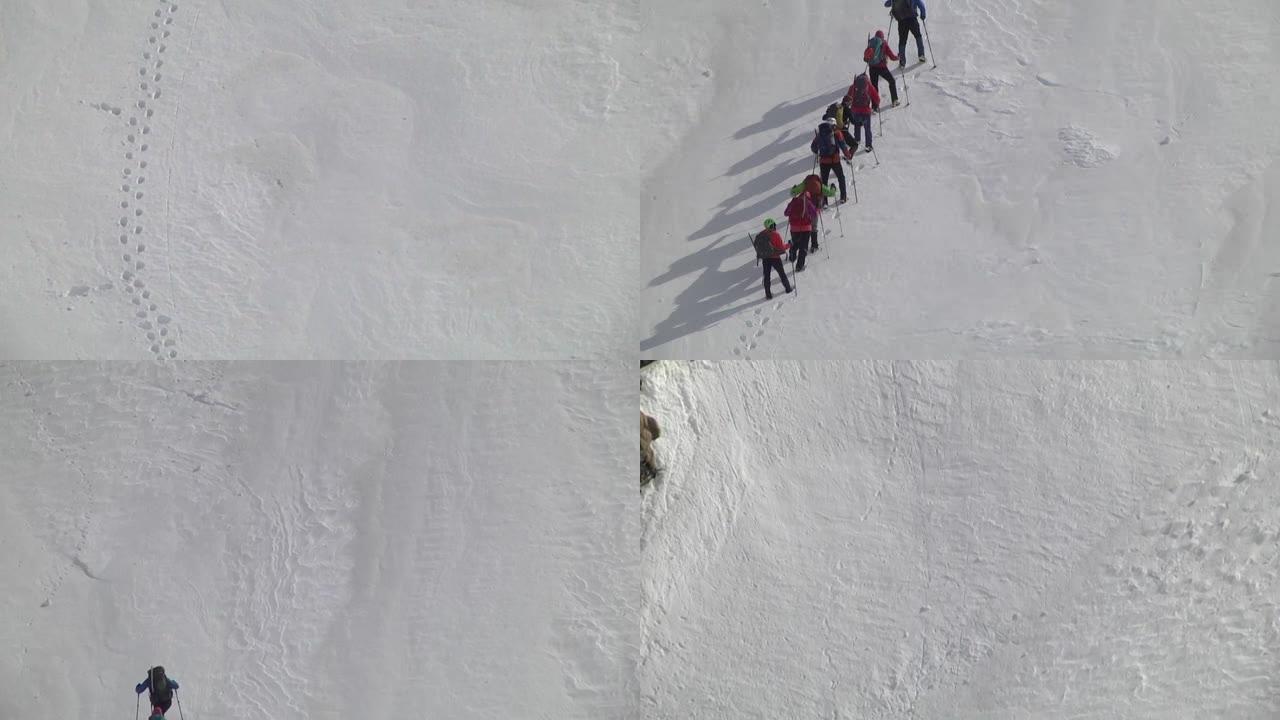 在印度26号线行走的一群游客的山坡陡峭上升上的雪地上的脚印