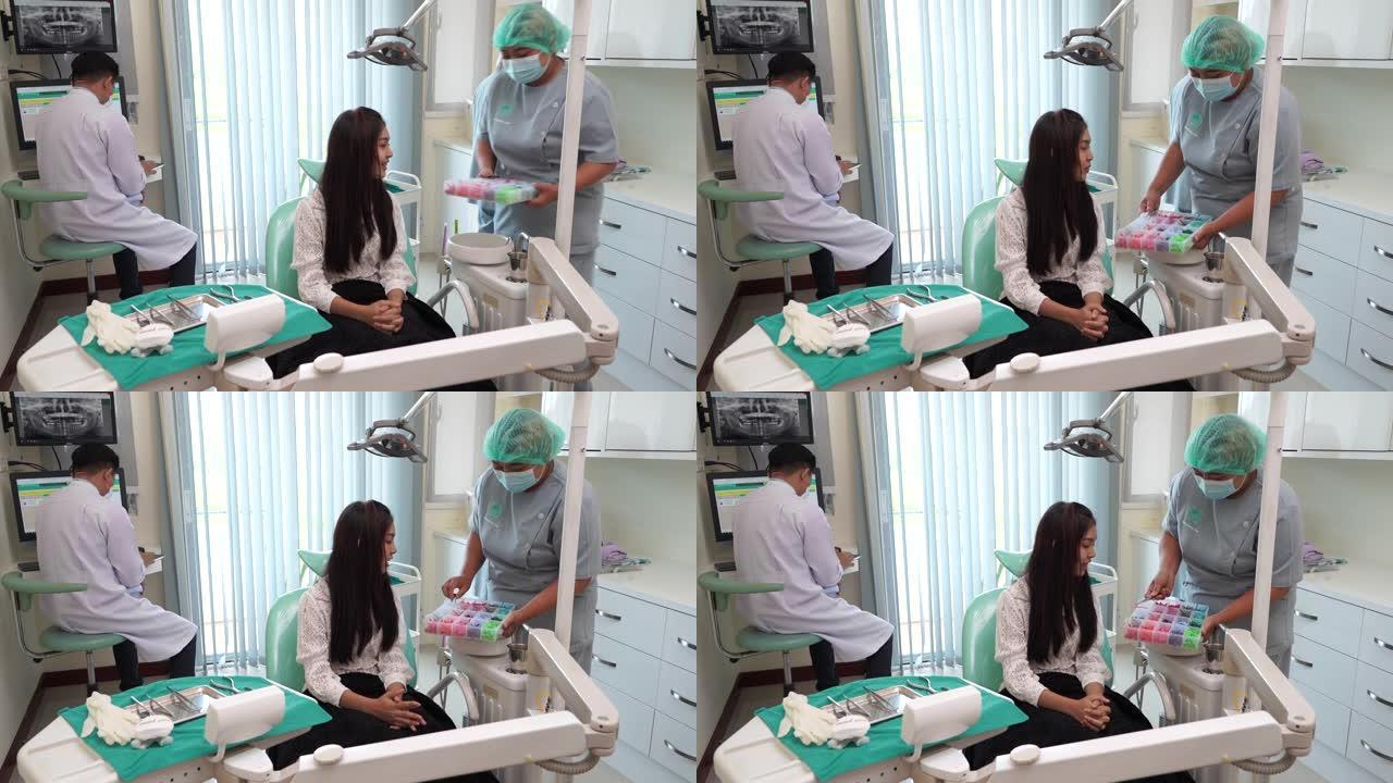 亚洲妇女选择橡胶支架与助理牙医在牙科诊所，正畸治疗。