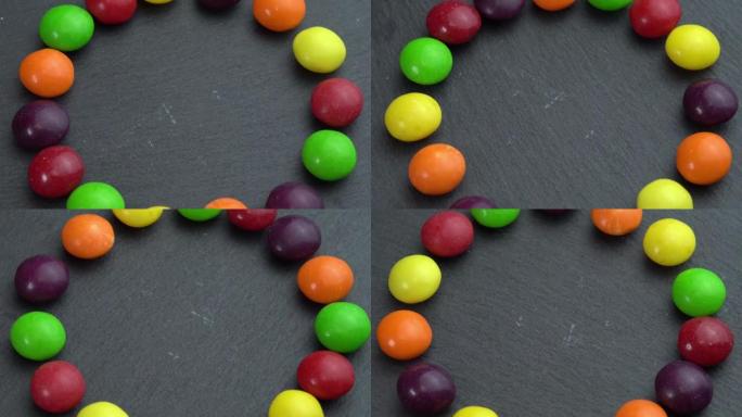 彩色糖果在黑色背景上旋转，手拿一个糖果，彩色糖果