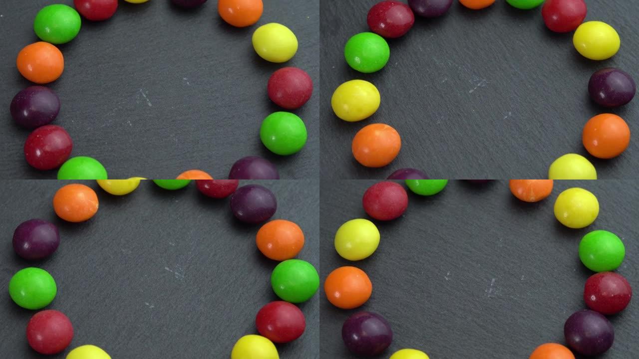 彩色糖果在黑色背景上旋转，手拿一个糖果，彩色糖果