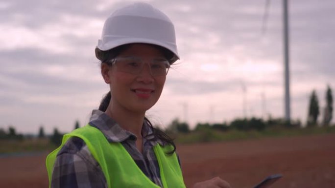 女性工程师使用智能手机在风力涡轮机农场工作的视频。