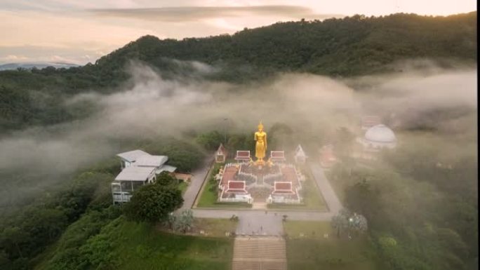 泰国宋卡府哈蒂区日出时山上大佛像周围移动雾的空中无人机超失效电影