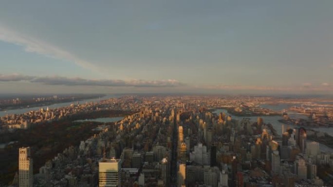 在黄金时段高空飞行。夕阳照亮了城市景观。两边被河流包围的土地。美国纽约市曼哈顿