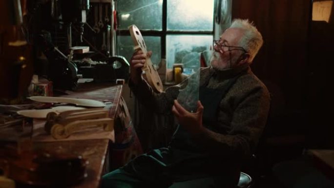 傍晚，一位退休的老工匠在他的车间里制作手工小提琴。