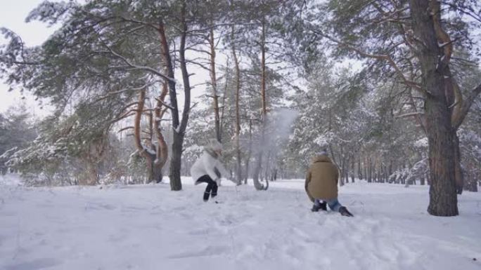 穿着暖和冬装的男孩和女孩正在打雪球，笑着玩得开心。幸福的夫妇喜欢在冬季白雪皑皑的松树林中散步。晴天在