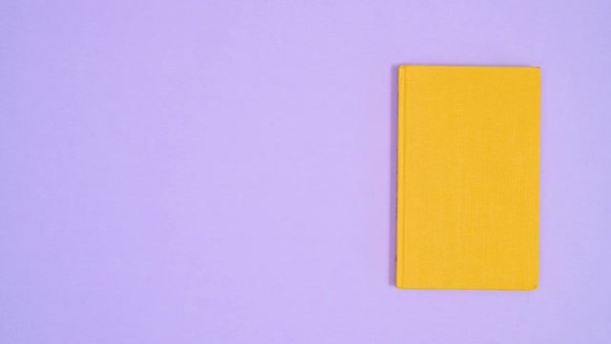 黄色精装复古复古书籍在紫色主题上向左向右移动。停止运动平铺