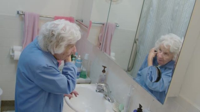 一位百岁老妇在照镜子，梳着头发
