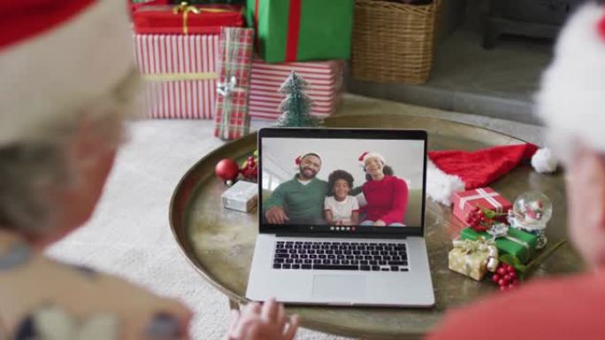 高级高加索夫妇使用笔记本电脑与屏幕上的幸福家庭进行圣诞节视频通话