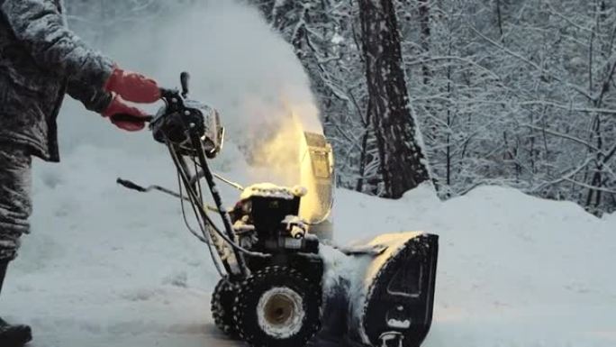 冰雪覆盖的男子冬季用鼓风机、除雪设备清理道路