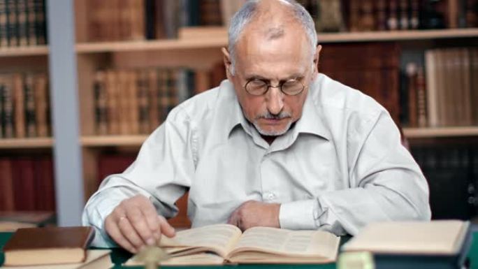 在公共图书馆的书桌前，沉思的70年代的爷爷读着老式的纸质书
