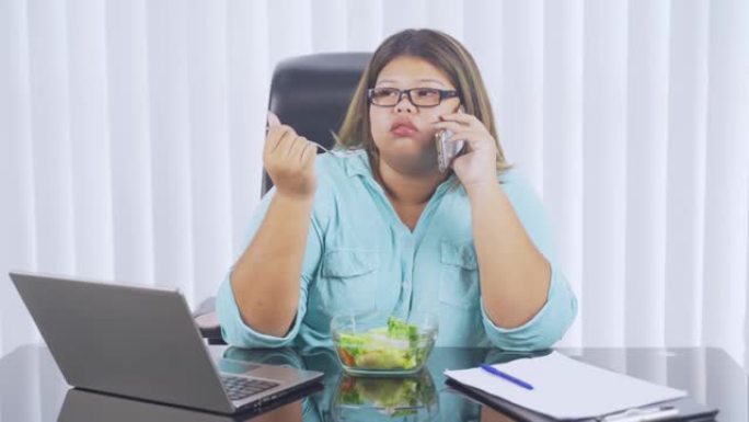 女人在吃沙拉时在手机上聊天