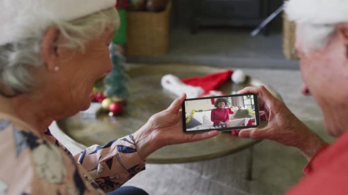 高级高加索夫妇使用智能手机与屏幕上的幸福女人进行圣诞节视频通话