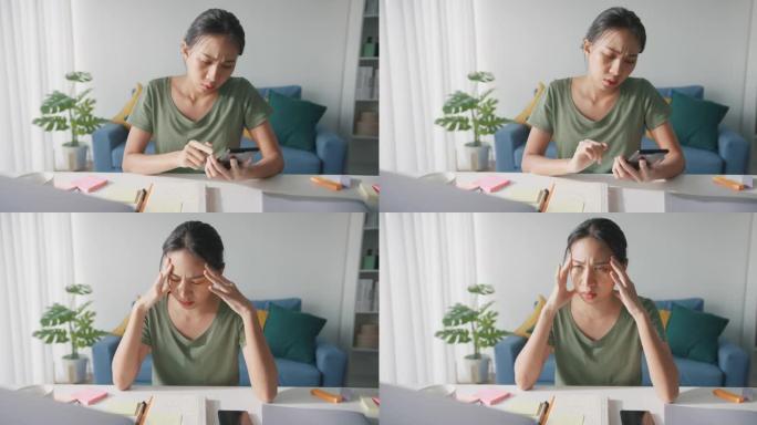 疲惫的年轻亚洲女商人在家里客厅随意使用电话。