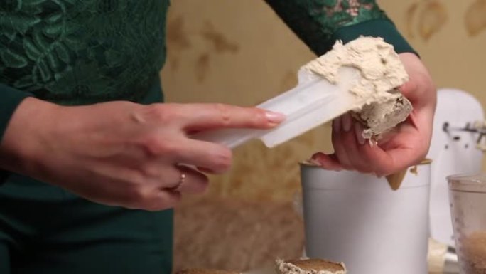 一个女人做饼干蛋糕。将黄油奶油涂在工件上。特写