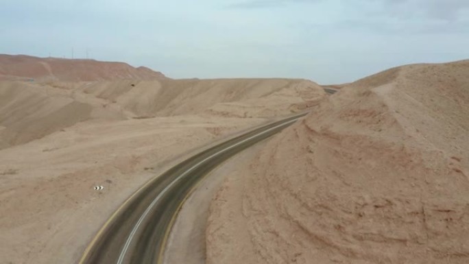 在荒芜地区的沙山之间的道路上，一辆面包车的汽车行驶