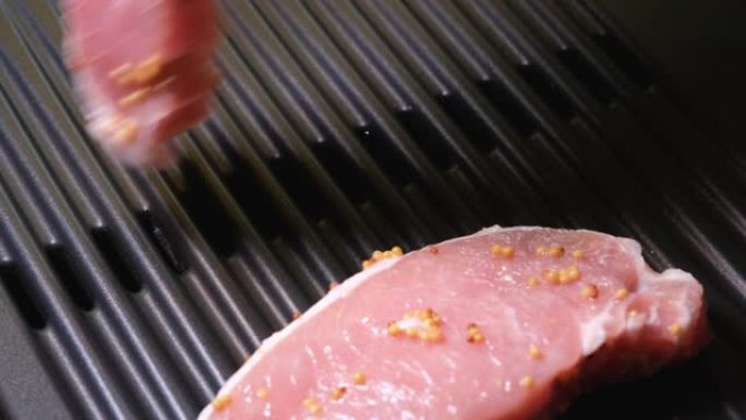 手工将猪排放在家庭烤架的表面上。4k分辨率视频。电动烤架和生猪肉特写。