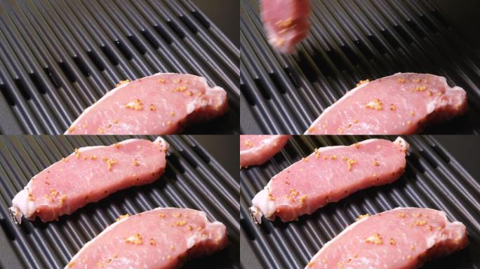 手工将猪排放在家庭烤架的表面上。4k分辨率视频。电动烤架和生猪肉特写。