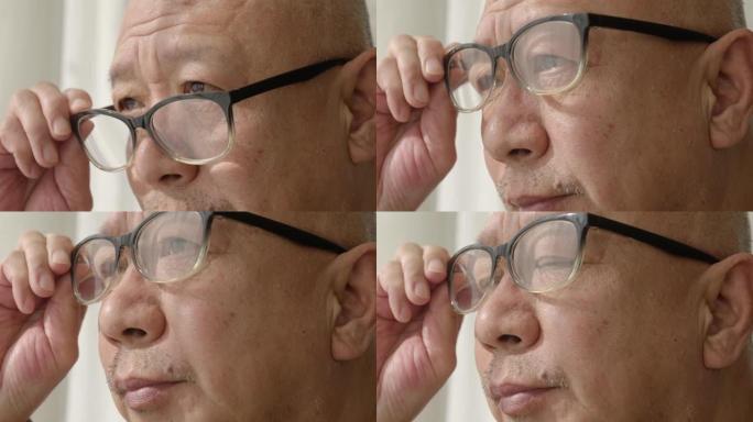 窗前的中国老人戴着老花镜，凝视着前方