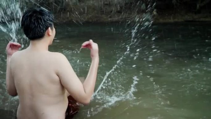 快乐的亚洲男孩在河里泼水，户外生活理念。