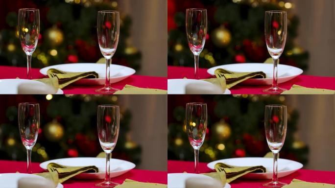 为庆祝新年或圣诞节而装饰的家庭舒适房间。蜡烛在节日的桌子上燃烧，盘子和香槟酒杯。关闭内部细节。慢动作