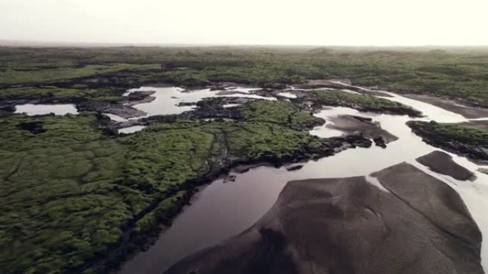 无人机在绿色熔岩场景观中的辫状河上飞行