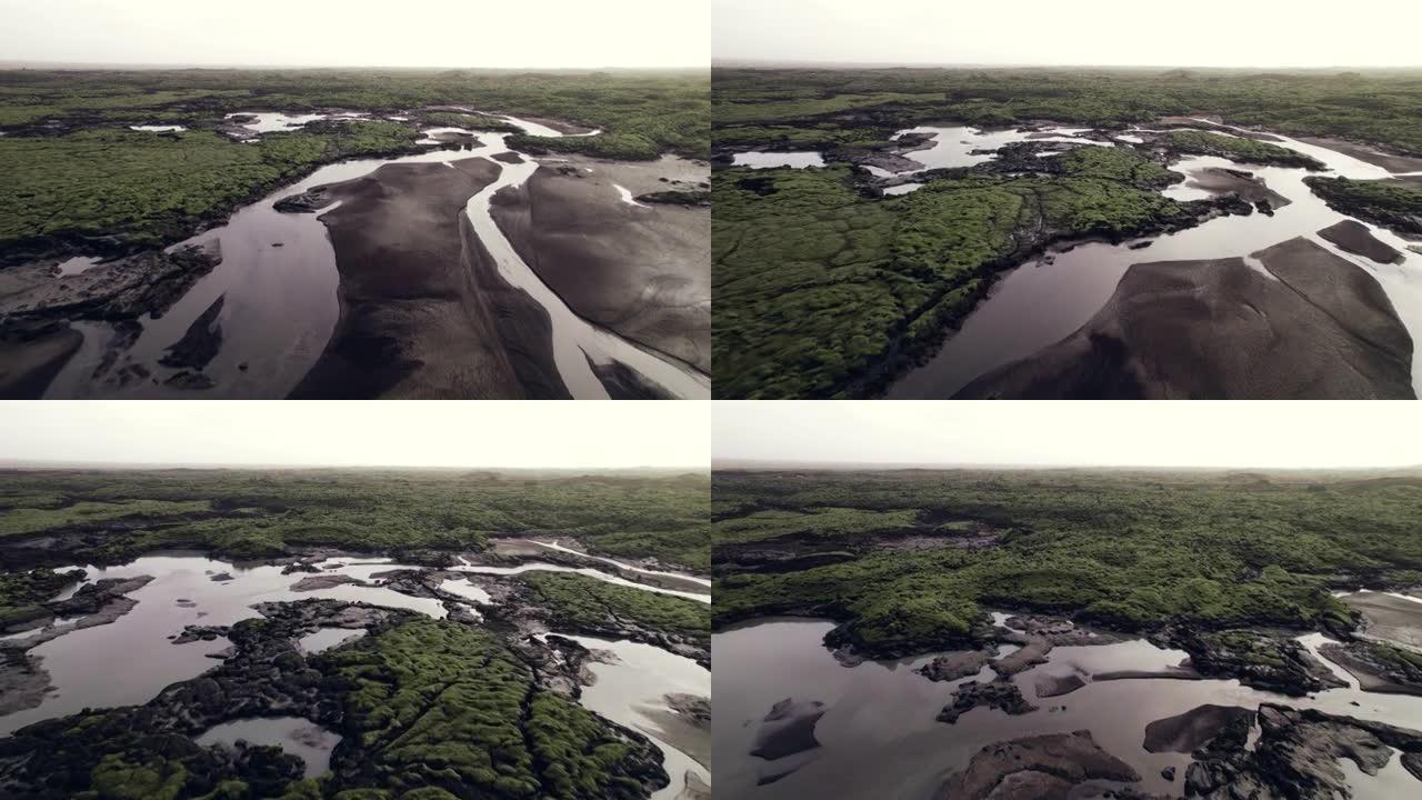 无人机在绿色熔岩场景观中的辫状河上飞行