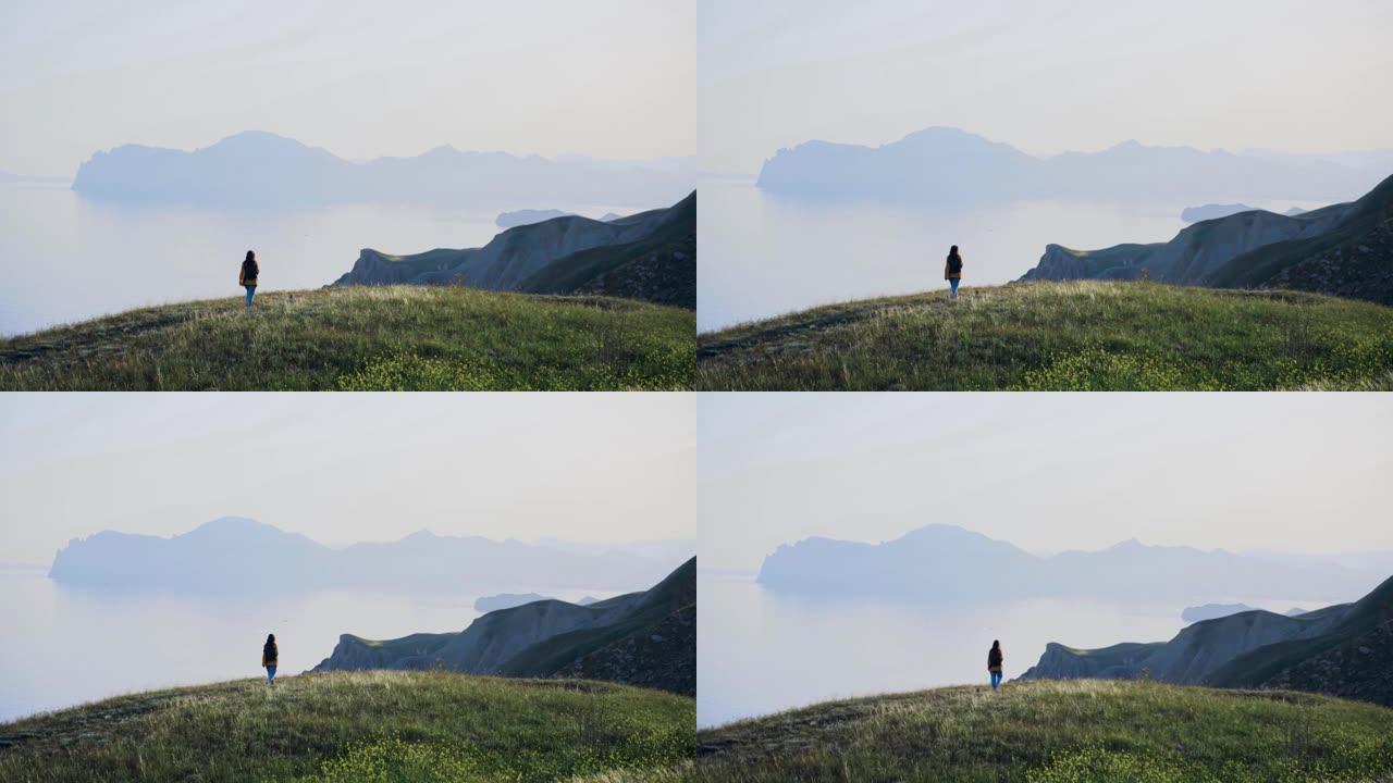 带着黑色包的背包客女士沿着绿色草地散步