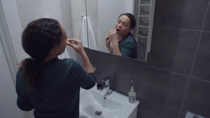 黑人妇女刷牙，跳舞，站在浴室的前镜子