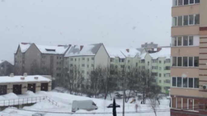 下雪了。在住宅建筑的背景下，大片雪花飘落的模糊背景。大雪纷飞。从公寓看