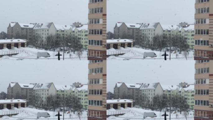 下雪了。在住宅建筑的背景下，大片雪花飘落的模糊背景。大雪纷飞。从公寓看