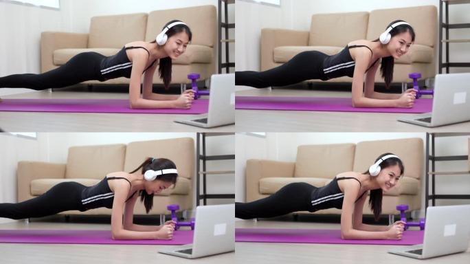 年轻的亚洲妇女在瑜伽垫上做铺板锻炼。体重训练对健康力量和力量。女性健美运动员和家里的肌肉锻炼。在笔记