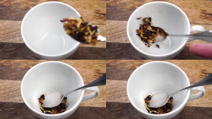 一茶匙将干草本水果花茶放在木桌上的白杯中
