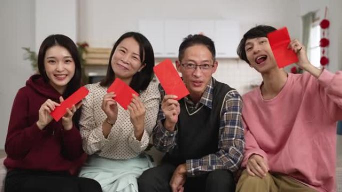 快乐的亚洲父亲，母亲，女儿和儿子在春节与朋友进行视频通话时，对着镜头微笑并炫耀手中的红包