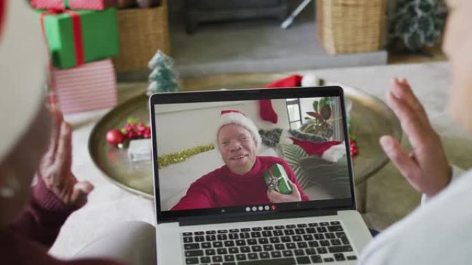 多元化的资深女性朋友使用笔记本电脑进行圣诞节视频通话，屏幕上有微笑的男人